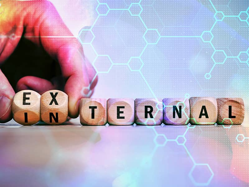 Wooden blocks spelling 'internal' and 'external' with a hand adjusting letters